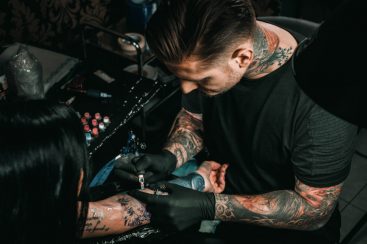 Professional tattoo artist makes a tattoo on a young girl’s hand